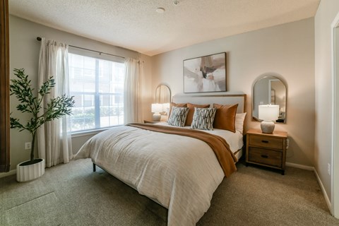 A bedroom with a large bed and a potted plant.