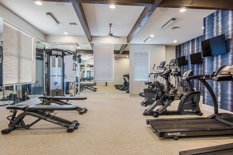 a gym with treadmills and other exercise equipments in a room with windows at The McKenzie Park Apartments, Little Rock