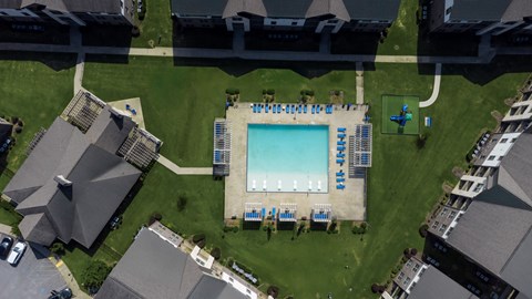 An aerial view of a swimming pool surrounded by lounge chairs and buildings.