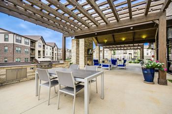 A patio with a table and chairs under a wooden pergola.