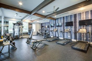 A gym with treadmills, weights, and exercise equipment.
