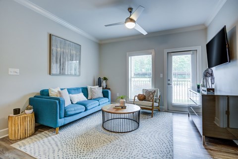 A living room with a blue couch, a coffee table, and a ceiling fan.