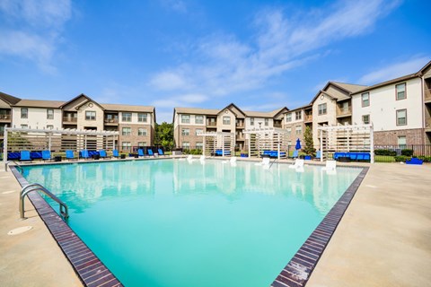 A large swimming pool in front of apartment buildings.