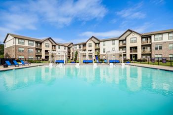 A large swimming pool in front of apartment buildings.
