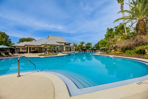 A large swimming pool with a slide and a building in the background.