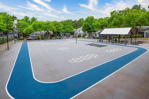 A blue and white painted basketball court in a park.