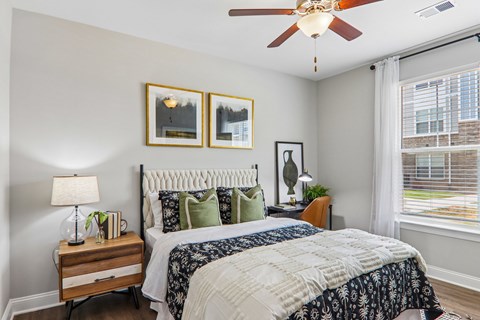 A bedroom with a large bed and a ceiling fan.