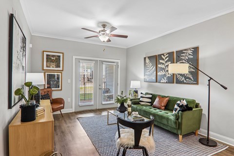 A living room with a green couch, a ceiling fan, and a wooden cabinet.