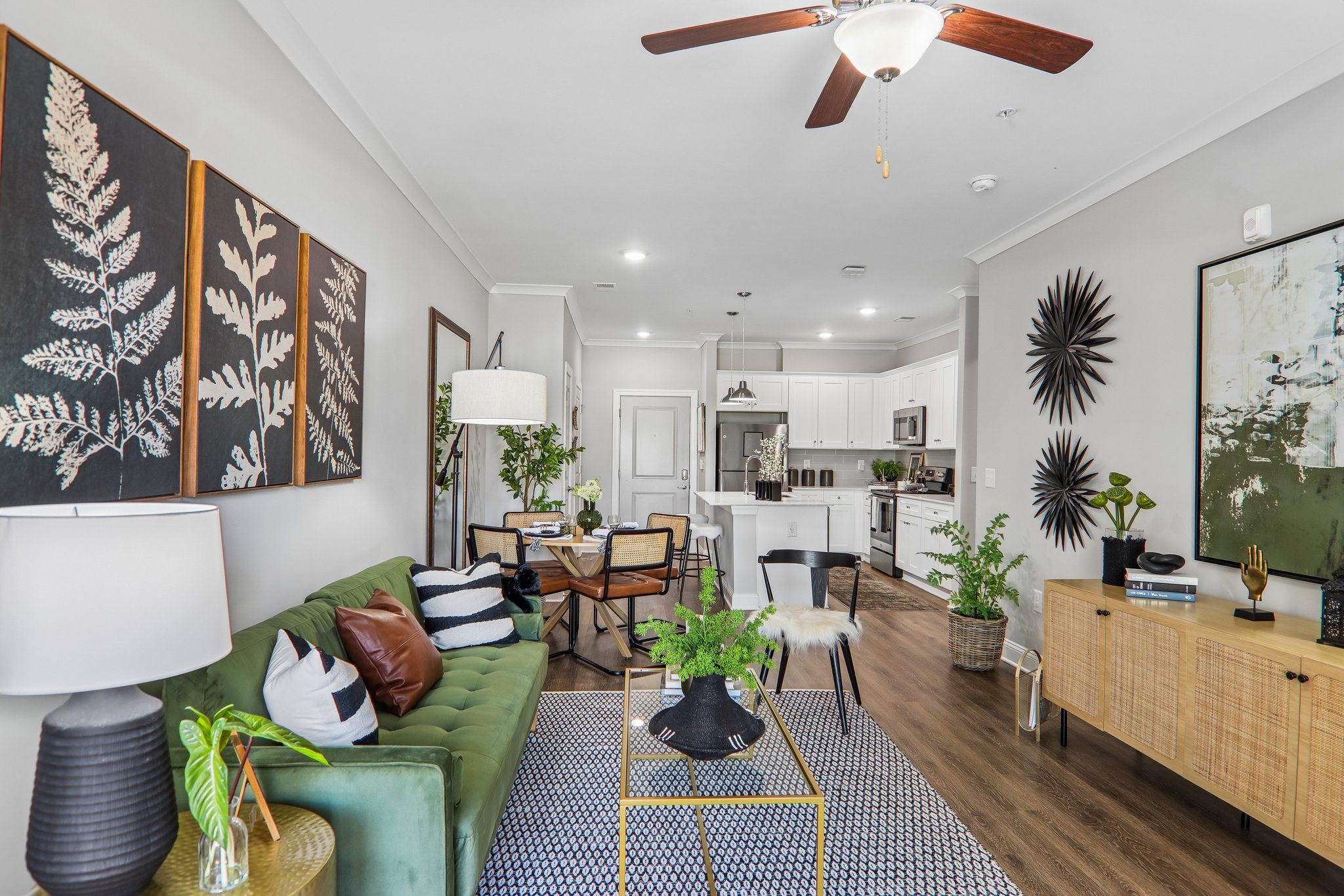 A living room with a green couch and a black and white rug.
