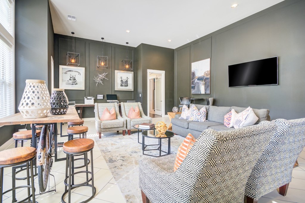A living room with a grey couch and a television on the wall.