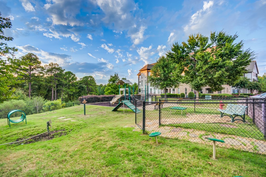A playground with a green slide and a fence.