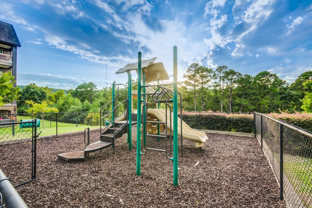 A playground with a yellow slide and a green pole.