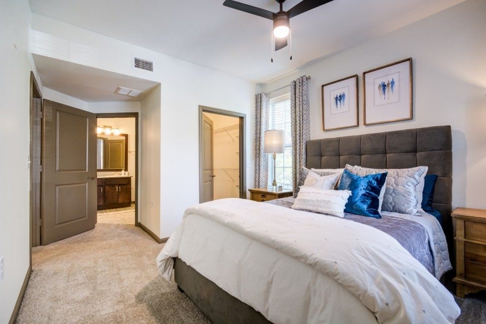 A bedroom with a large bed and a ceiling fan.