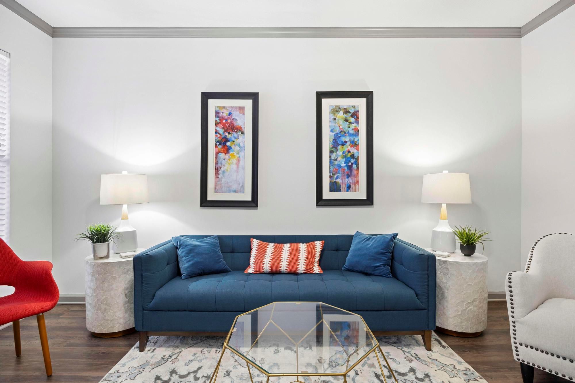 A living room with a blue couch and two framed artworks on the wall.