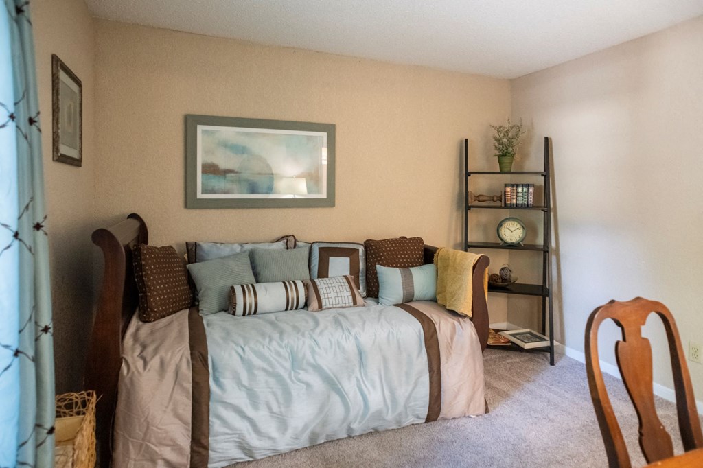 a bedroom with a bed with pillows and a shelf with a clock at The Summit Apartments, Memphis
