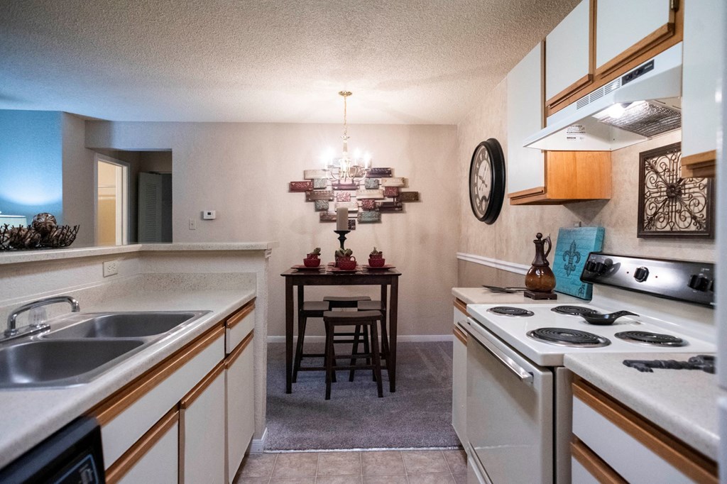 a kitchen with white appliances and a dining room with a table at The Summit Apartments, Memphis, Tennessee