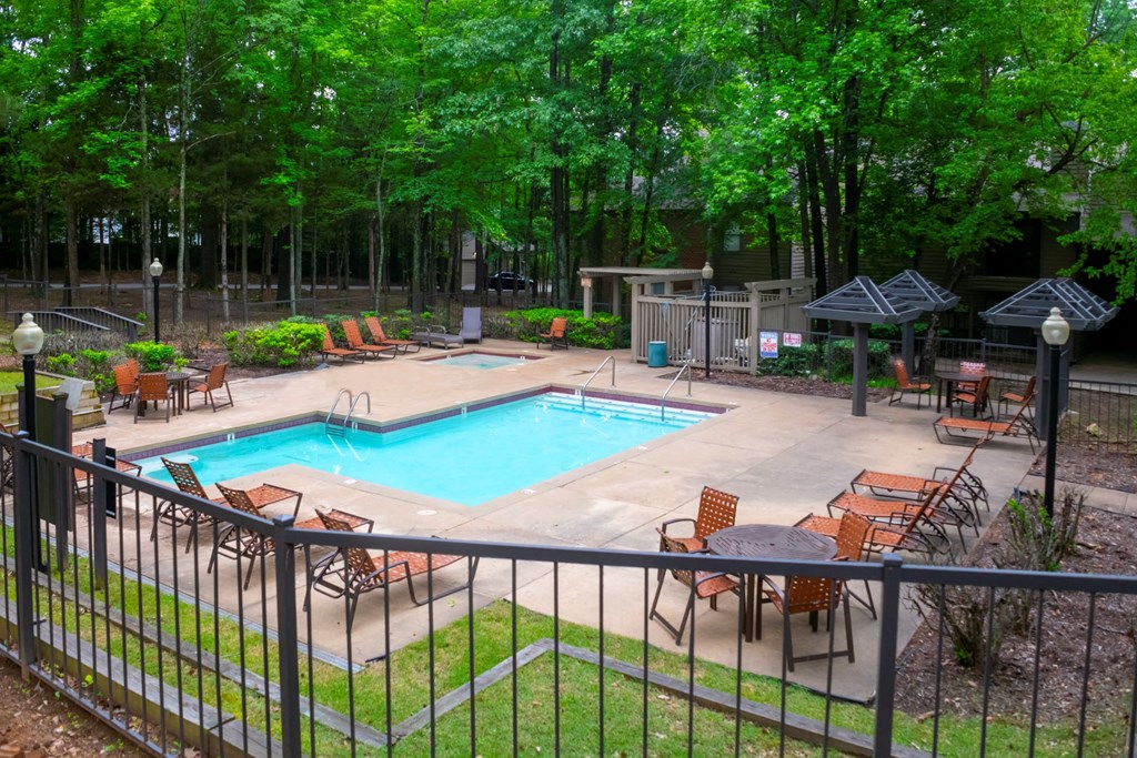 a swimming pool with chairs around it and a patio with trees at The Summit Apartments, Memphis, Tennessee