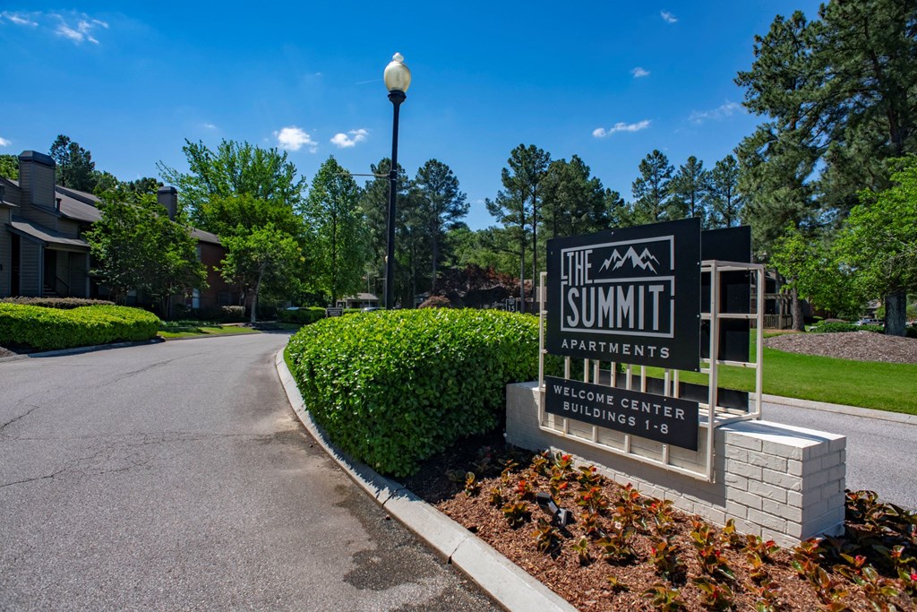 the summit apartments sign in front of a road with trees at The Summit Apartments, Memphis