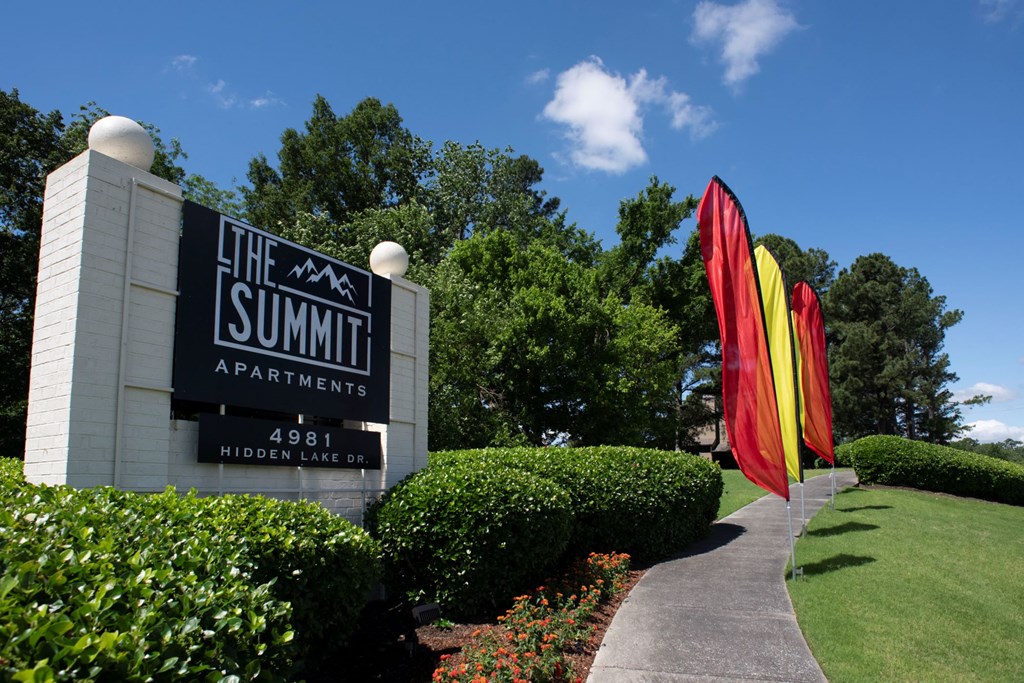 the sign for the summit apartments in front of a lawn with colorful umbrellas at The Summit Apartments, Tennessee