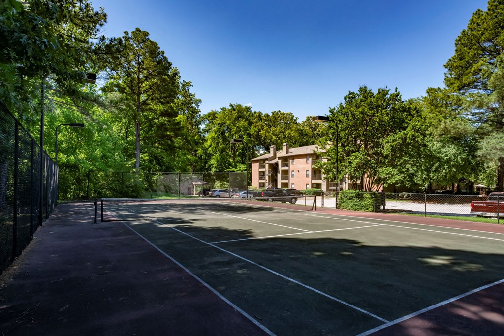 a tennis court with a building in the background at The Summit Apartments, Tennessee
