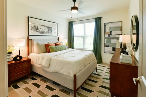 A bedroom with a bed, nightstand, and a ceiling fan.