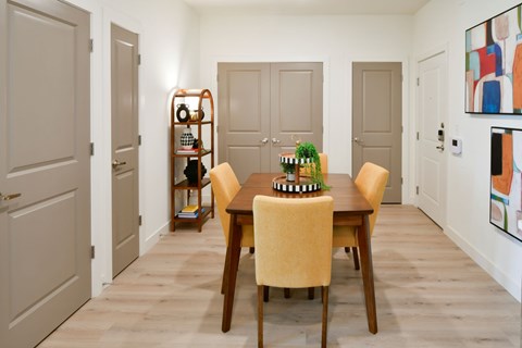 A dining room with a table set for two and a bookshelf.