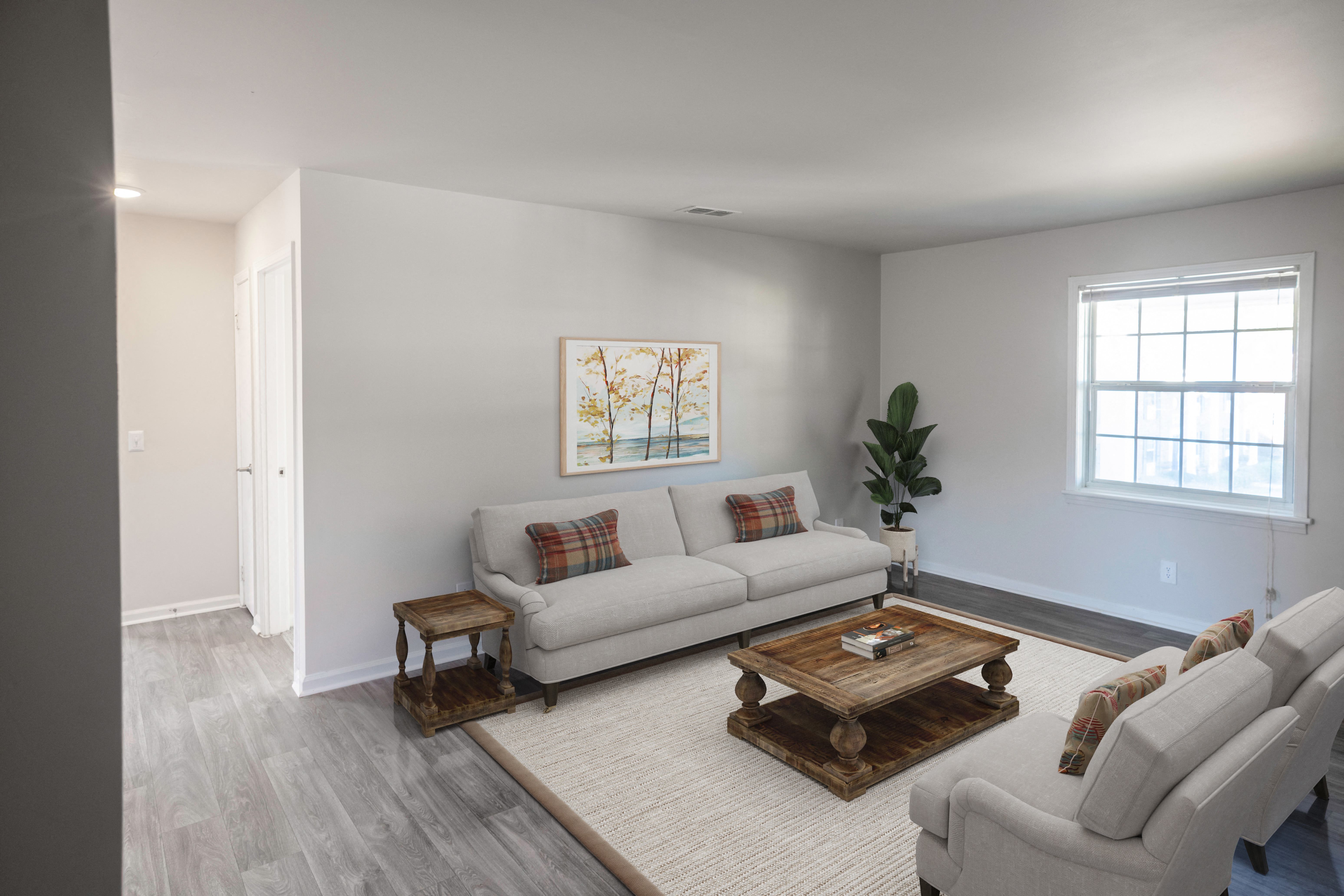 A living room with a white couch, a wooden coffee table, and a painting on the wall.