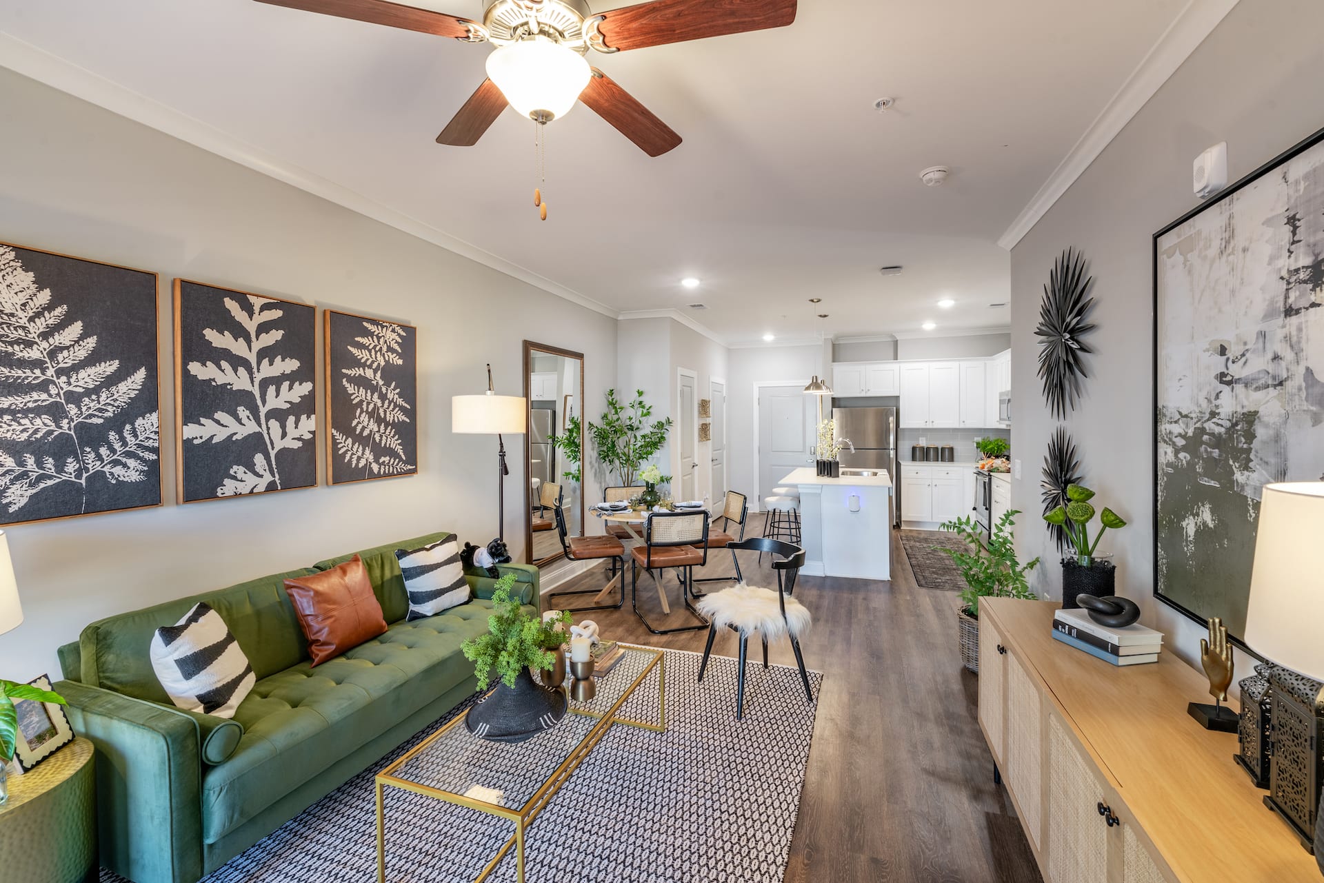 A living room with a green couch and a fan on the ceiling.
