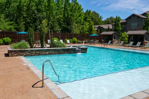 A swimming pool surrounded by trees and a fence.