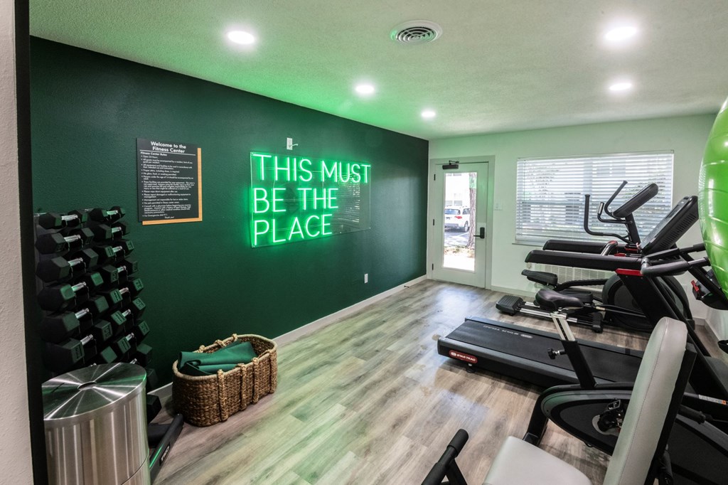 A gym with a green wall and a sign that says "This must be the place".