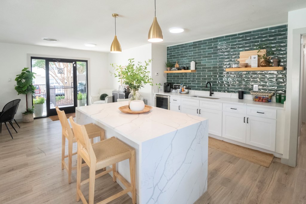 A kitchen with a white marble island and wooden chairs.