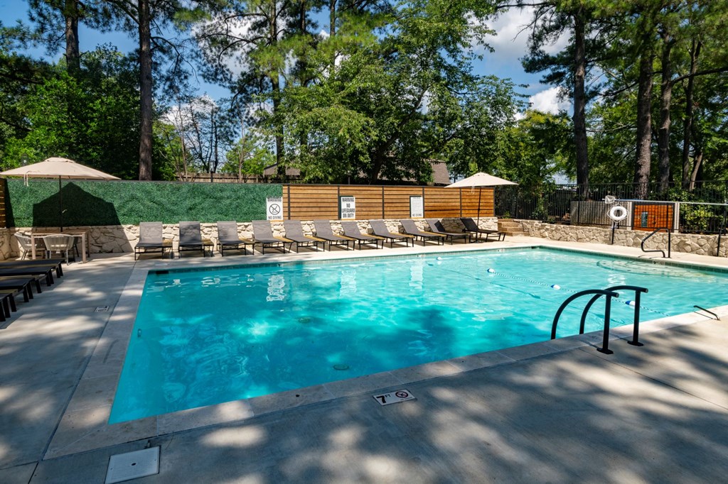 A large outdoor swimming pool surrounded by trees.