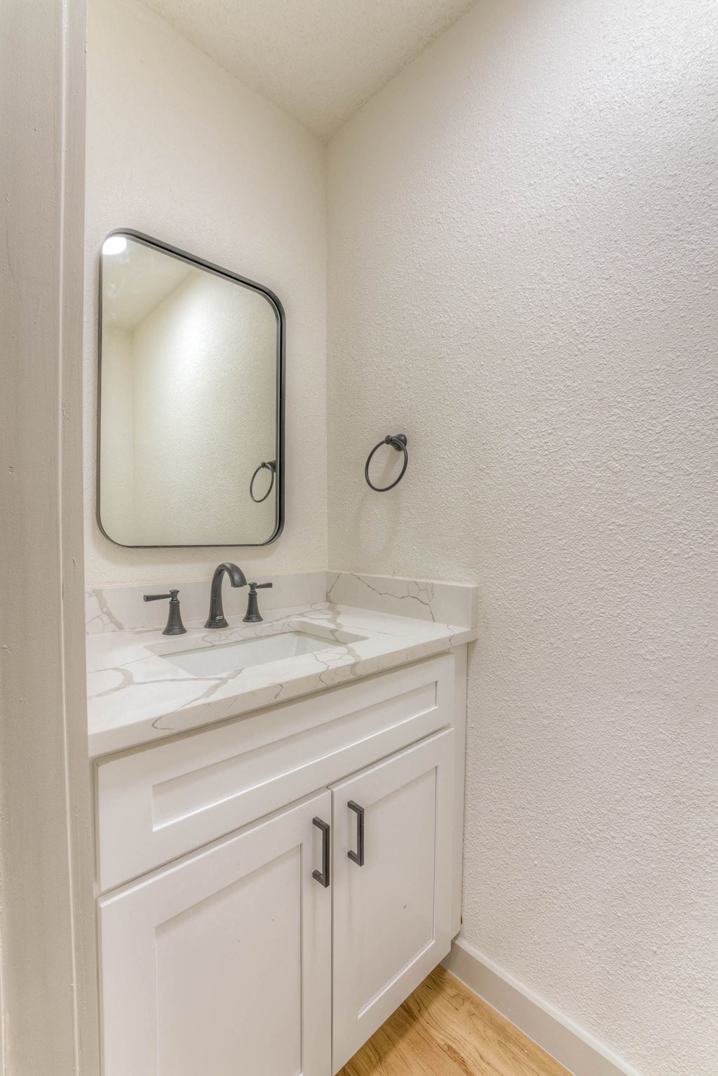 A white bathroom with a sink and a mirror.at The Garden District Apartments, Germantown, TN 38138  