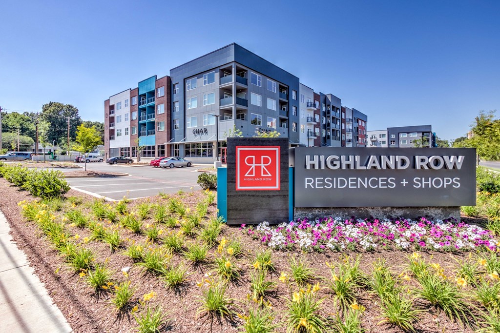 A sign for Highland Row Residences and Shops is in front of a building. A sign for Highland Row Residences and Shops is in front of a building at Highland Row Apartments, Memphis, TN, 38111