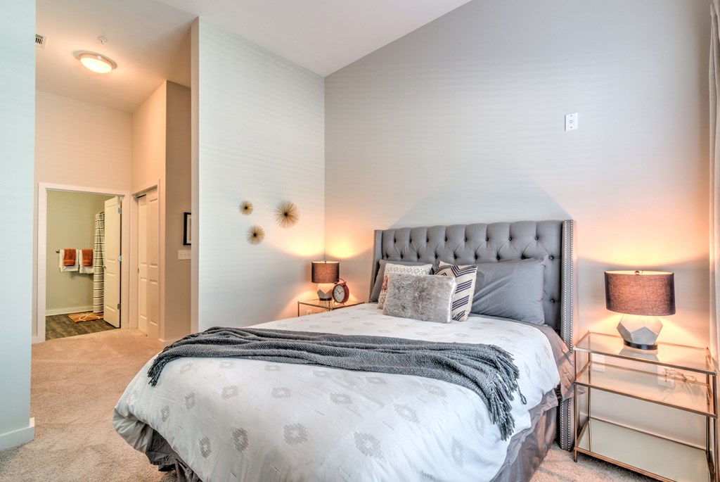 A bedroom with a large bed and a nightstand with a lamp at Highland Row Apartments, Memphis, TN,  38111