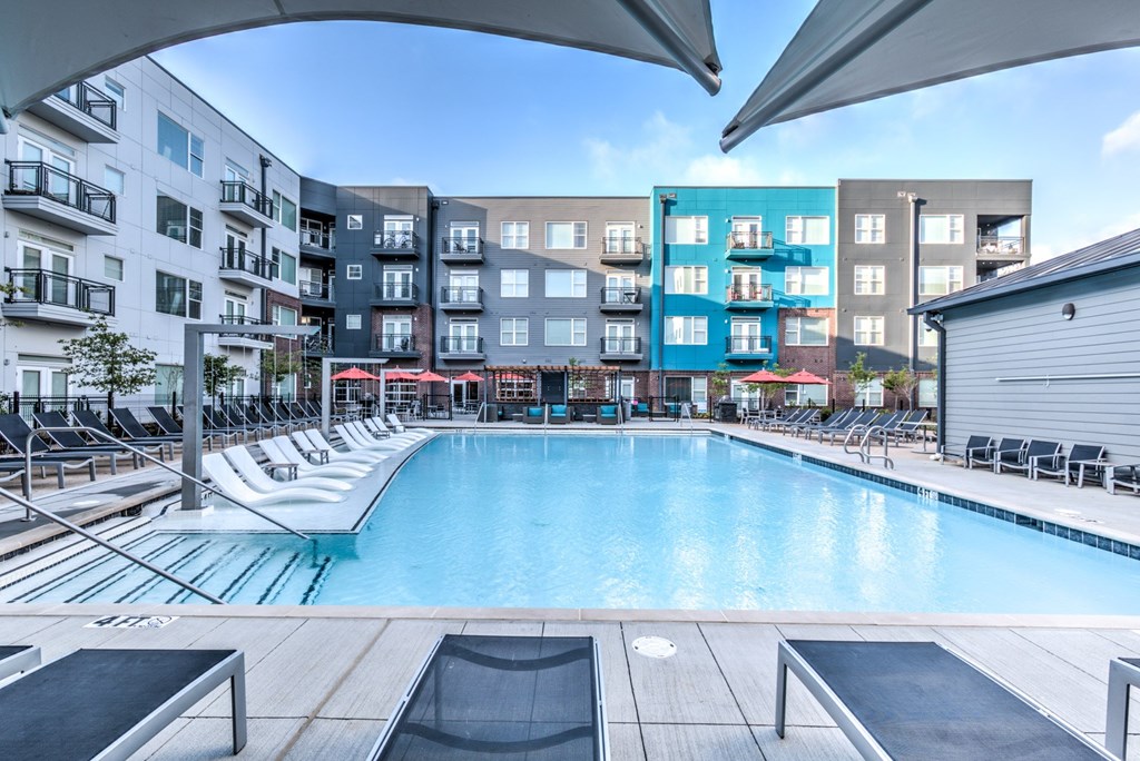 A large outdoor swimming pool surrounded by lounge chairs and umbrellas A large outdoor swimming pool surrounded by lounge chairs and umbrellas at Highland Row Apartments, Memphis, Tennessee