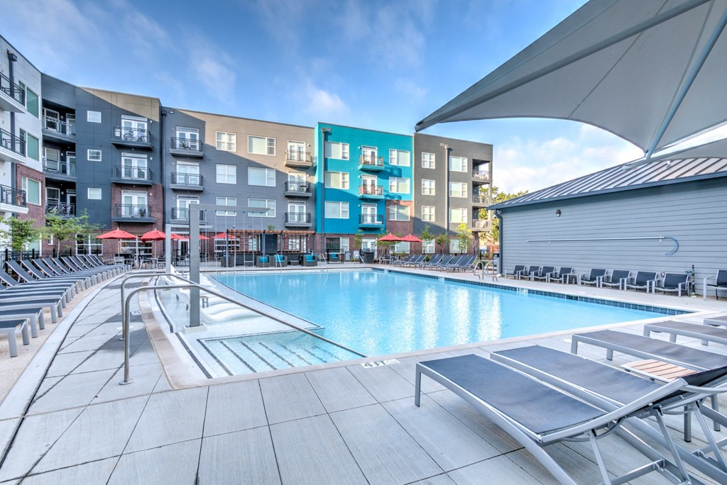 A swimming pool area with sun loungers and a building in the background at Highland Row Apartments, Tennessee
