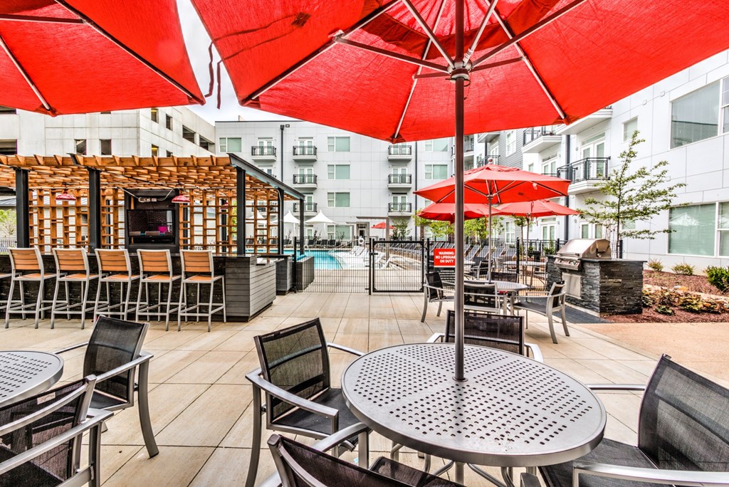 A patio with red umbrellas and chairs at Highland Row Apartments, Memphis