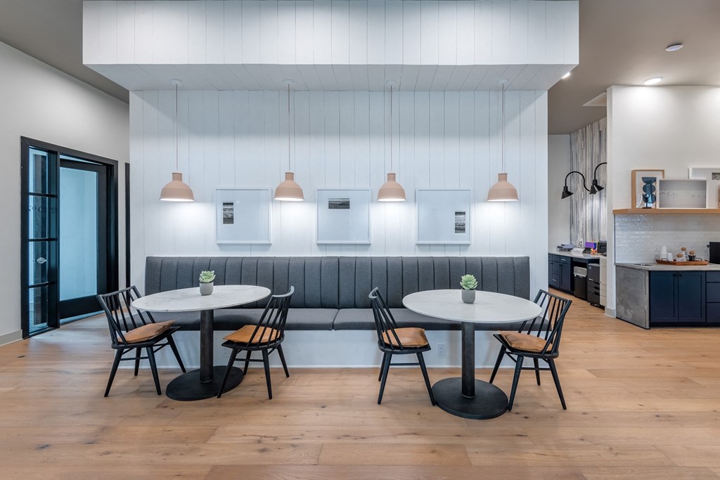 a dining area with two round tables and a kitchen in the background at The Livano Kemah, Kemah, TX, 77565