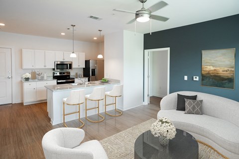 A modern kitchen with white cabinets and a bar area with stools.