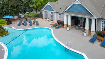 a swimming pool with chairs in front of a house