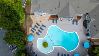 an aerial view of a swimming pool and patio with umbrellas