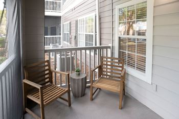 a porch with two wooden chairs and a table with a plant