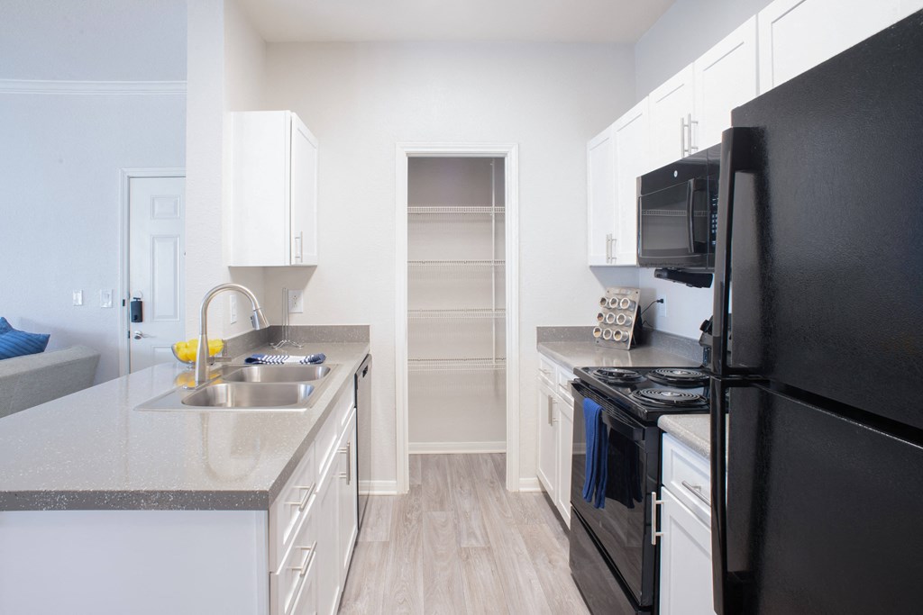 a kitchen with white cabinets and black appliances at Lincoln at Wolfchase, Tennessee