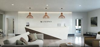 a reception area with a white couch and chairs and a reception desk with a large white counter at Livano Grand National, Orlando