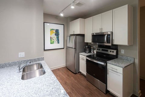 A kitchen with a stainless steel refrigerator, oven, and microwave.