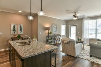 a kitchen with an island and a living room in the background at Meridian Park in Collierville, TN 38017