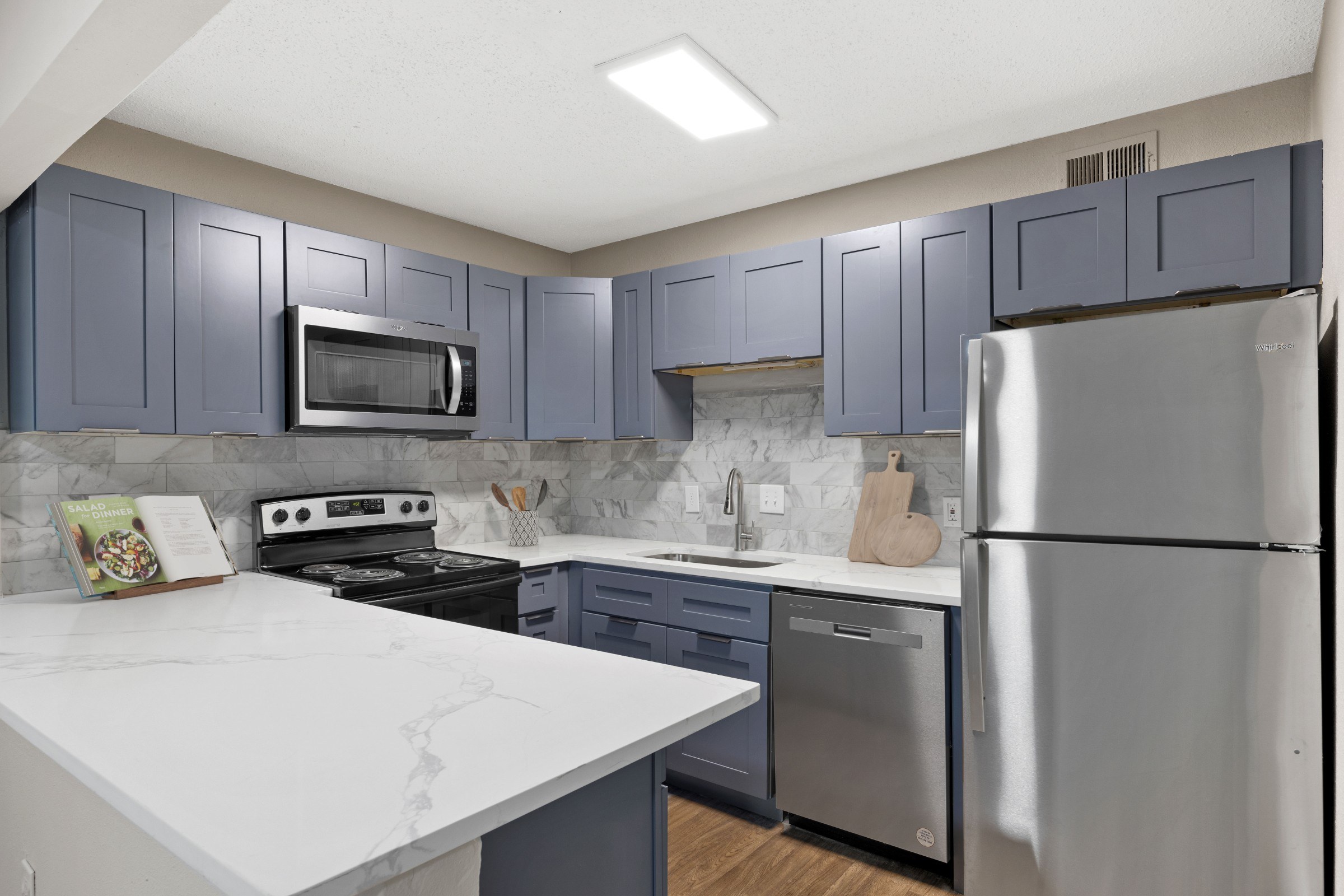 A kitchen with a white counter top and stainless steel appliances.