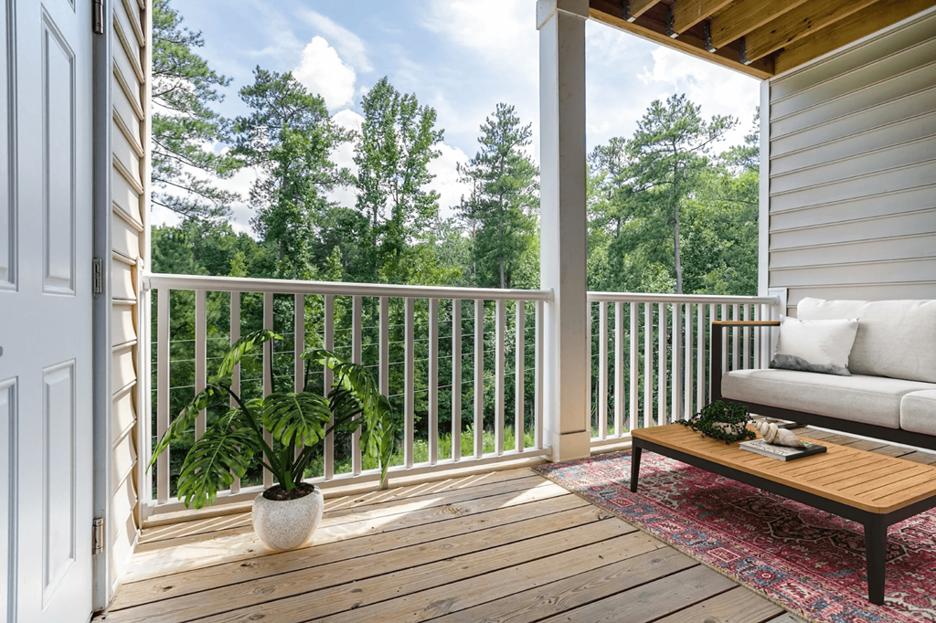 A wooden deck with a white sofa and a potted plant at Henley at Mirror Lake Apartments, Villa Rica 30180