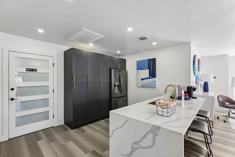 A kitchen with a marble counter top and a refrigerator with a glass door.